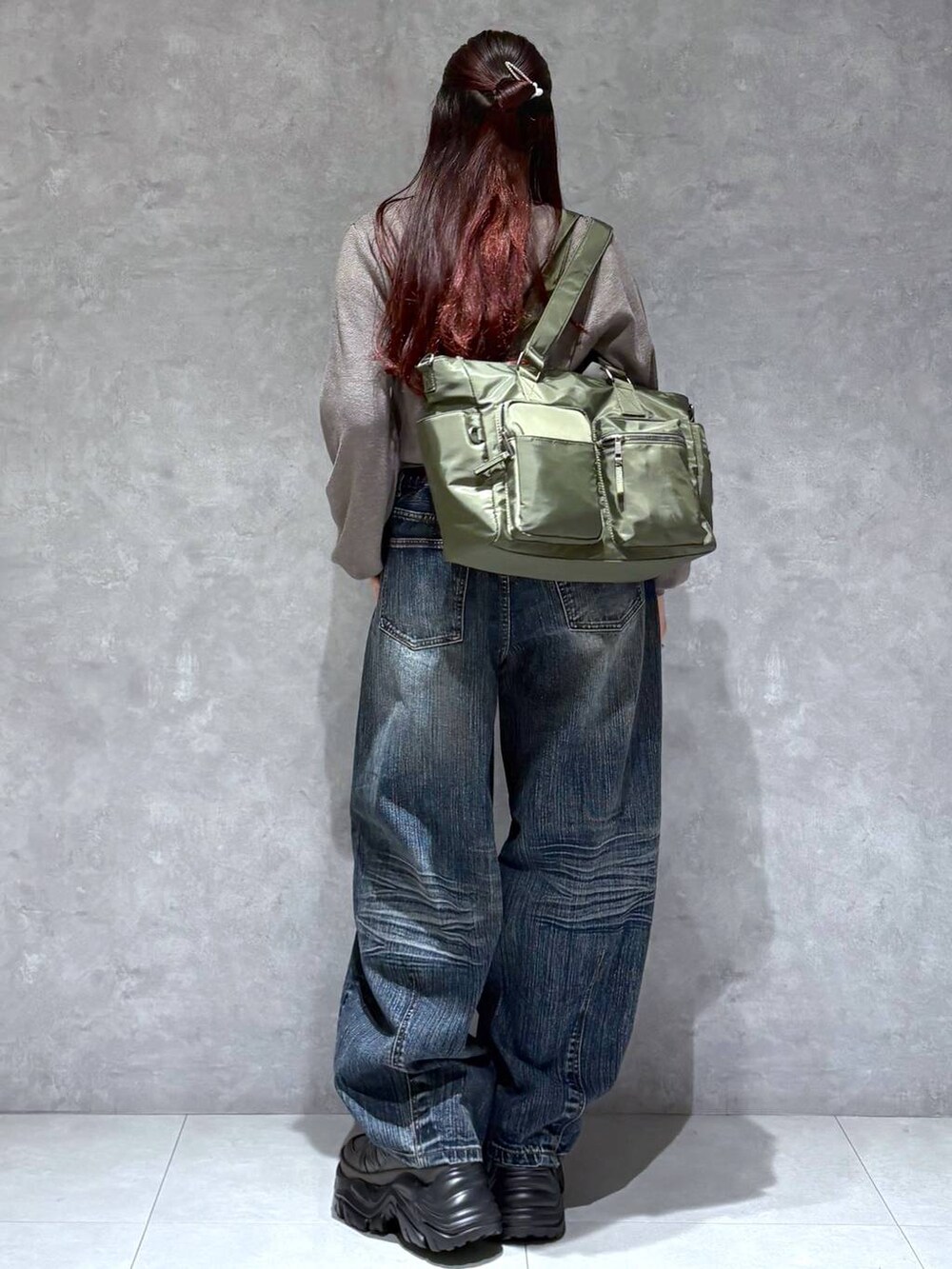 グレー系のスニーカー、グリーン系のボストンバッグ、ブルー系のデニムパンツを着用したレディースの秋コーディネートの5枚目の写真