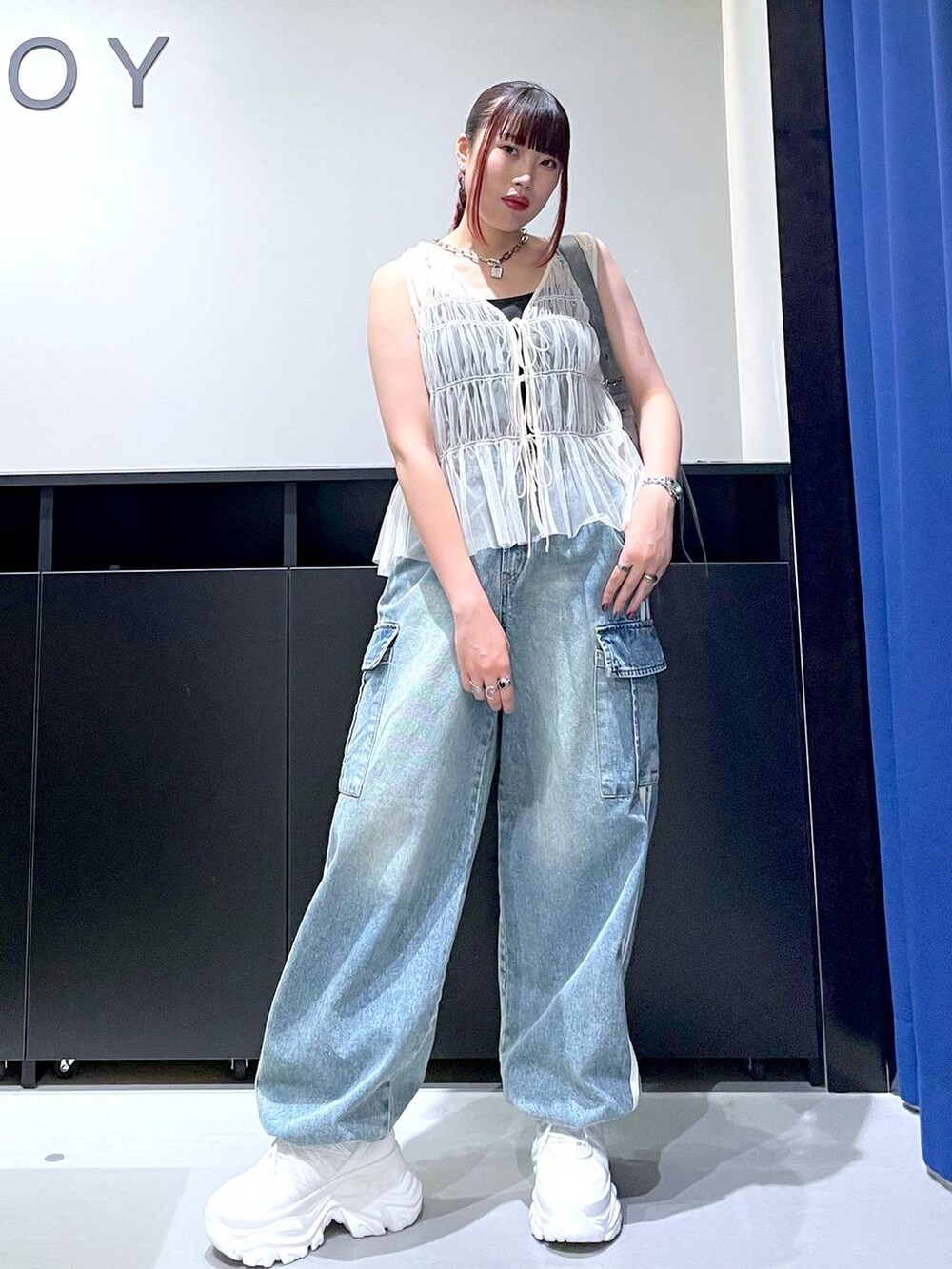 ホワイト系のスニーカー、ブルー系のデニムパンツ、グレー系のショルダーバッグを着用したレディースの夏コーディネートの3枚目の写真