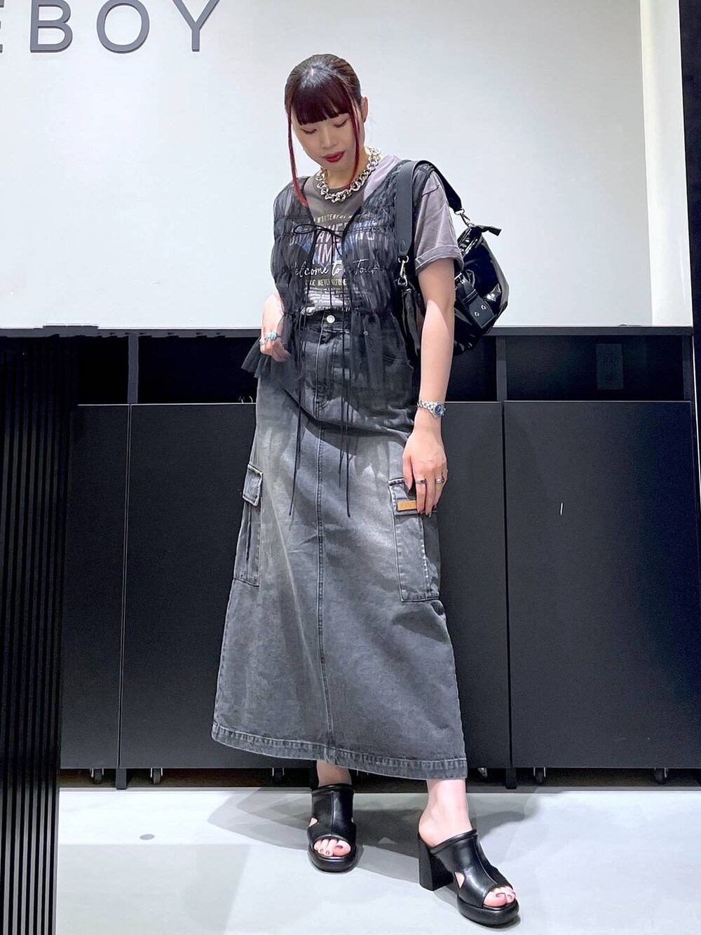 ブラック系のサンダル、ブラック系のデニムスカート、ブラック系のショルダーバッグを着用したレディースの夏コーディネートの6枚目の写真