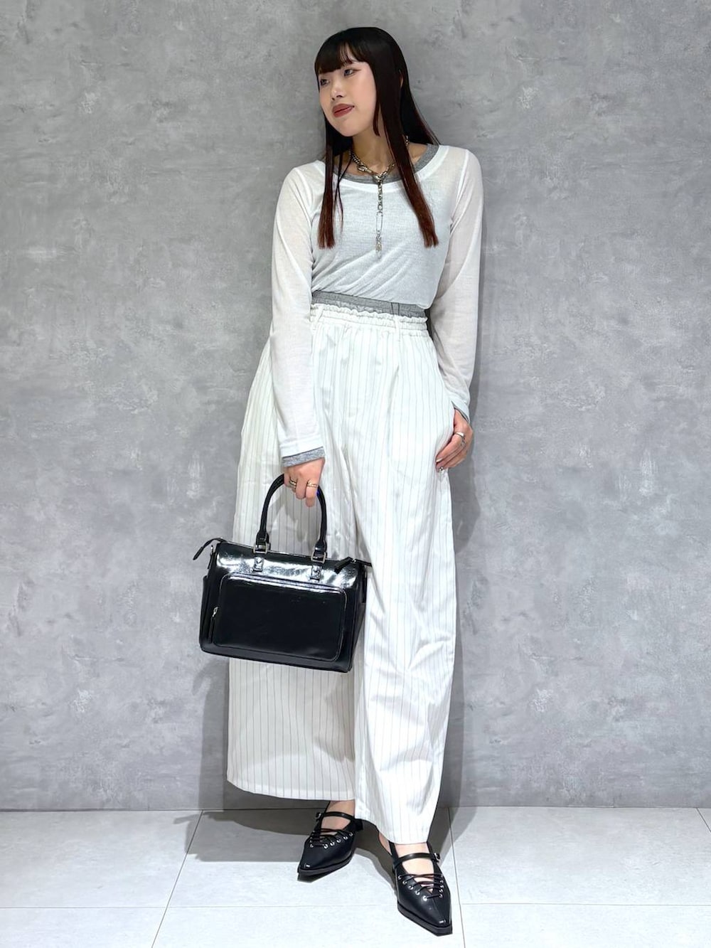 ブラック系のショルダーバッグ、ブラック系のサンダル、ホワイト系のスラックスを着用したレディースの冬コーディネートの9枚目の写真