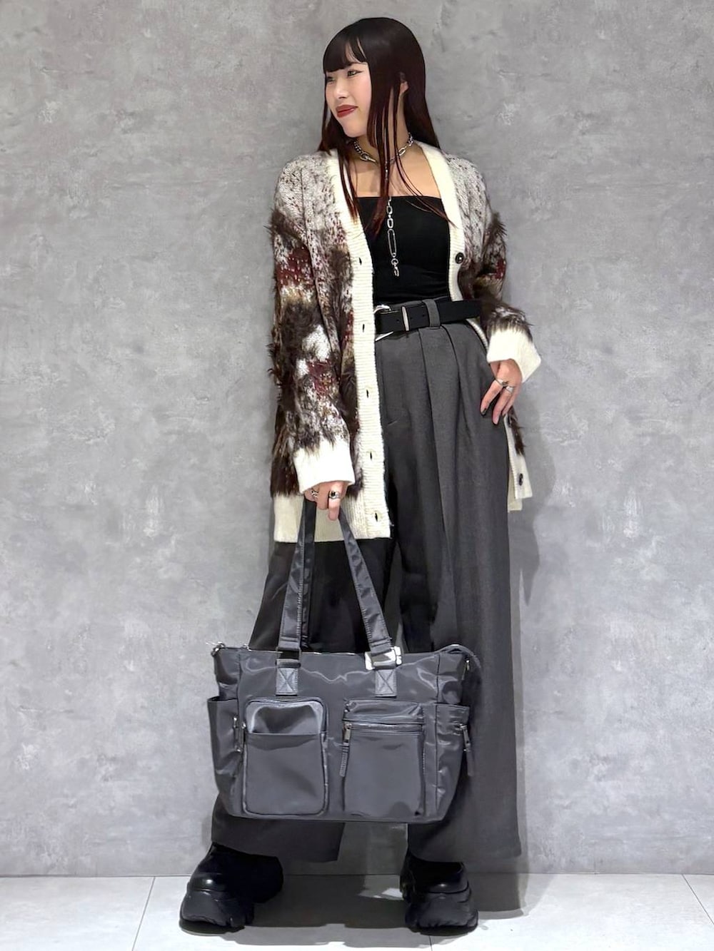 ブラック系のブーツ、グレー系のボストンバッグ、ホワイト系のカーディガン/ボレロを着用したレディースの秋コーディネートの2枚目の写真