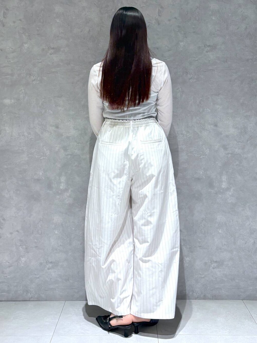 ブラック系のショルダーバッグ、ブラック系のサンダル、ホワイト系のスラックスを着用したレディースの冬コーディネートの4枚目の写真