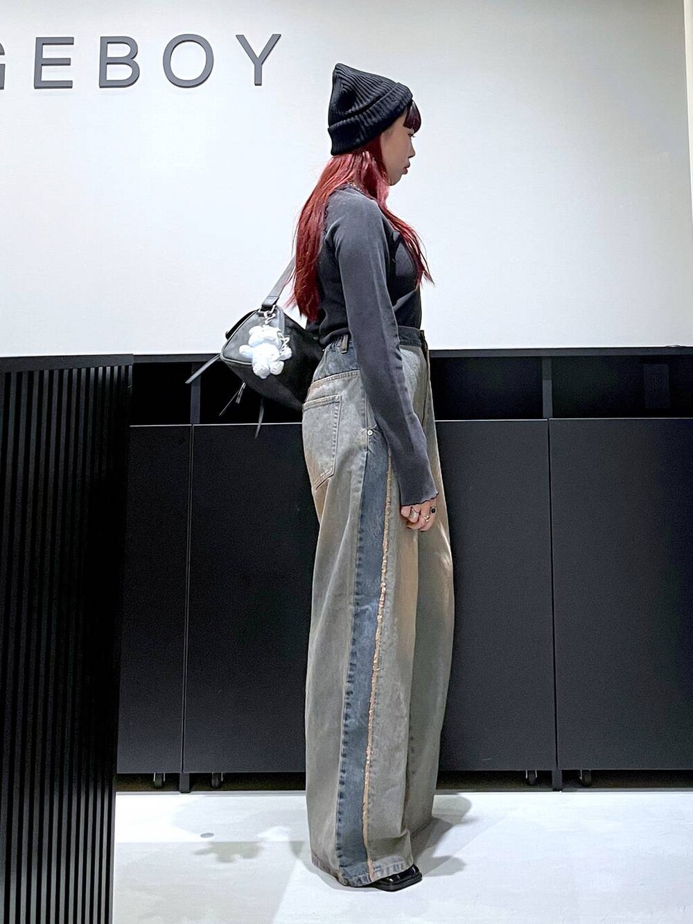 ブラック系のショルダーバッグ、ブルー系のデニムパンツ、ブラック系のブーツを着用したレディースの秋コーディネートの6枚目の写真