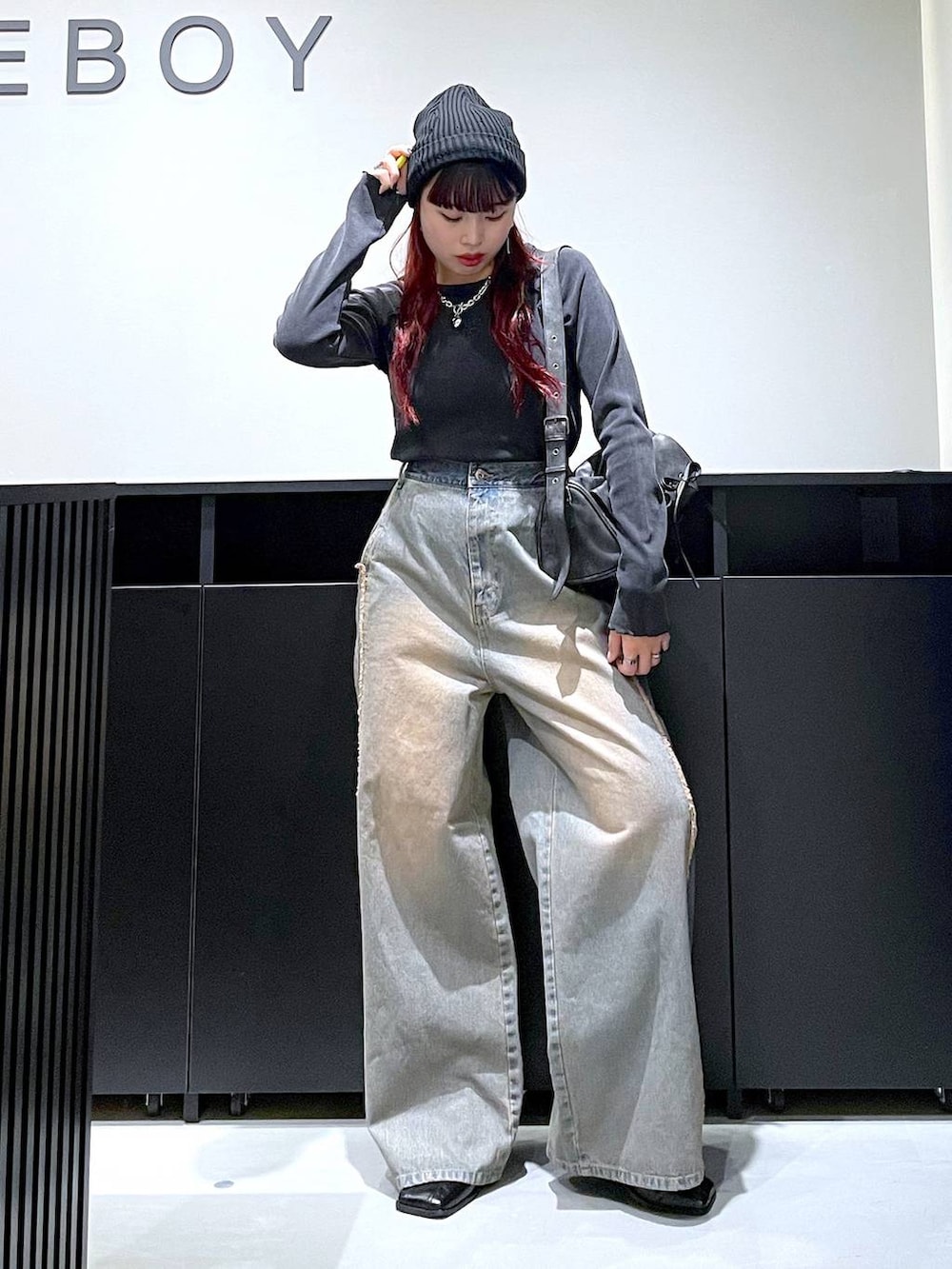 ブラック系のショルダーバッグ、ブルー系のデニムパンツ、ブラック系のブーツを着用したレディースの秋コーディネートの2枚目の写真