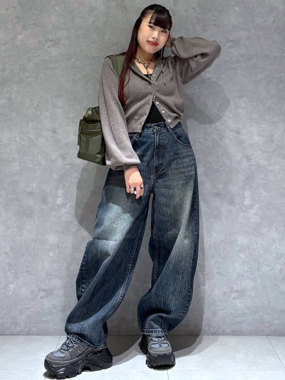グレー系のスニーカー、グリーン系のボストンバッグ、ブルー系のデニムパンツを着用したレディースの秋コーディネートの2枚目の写真
