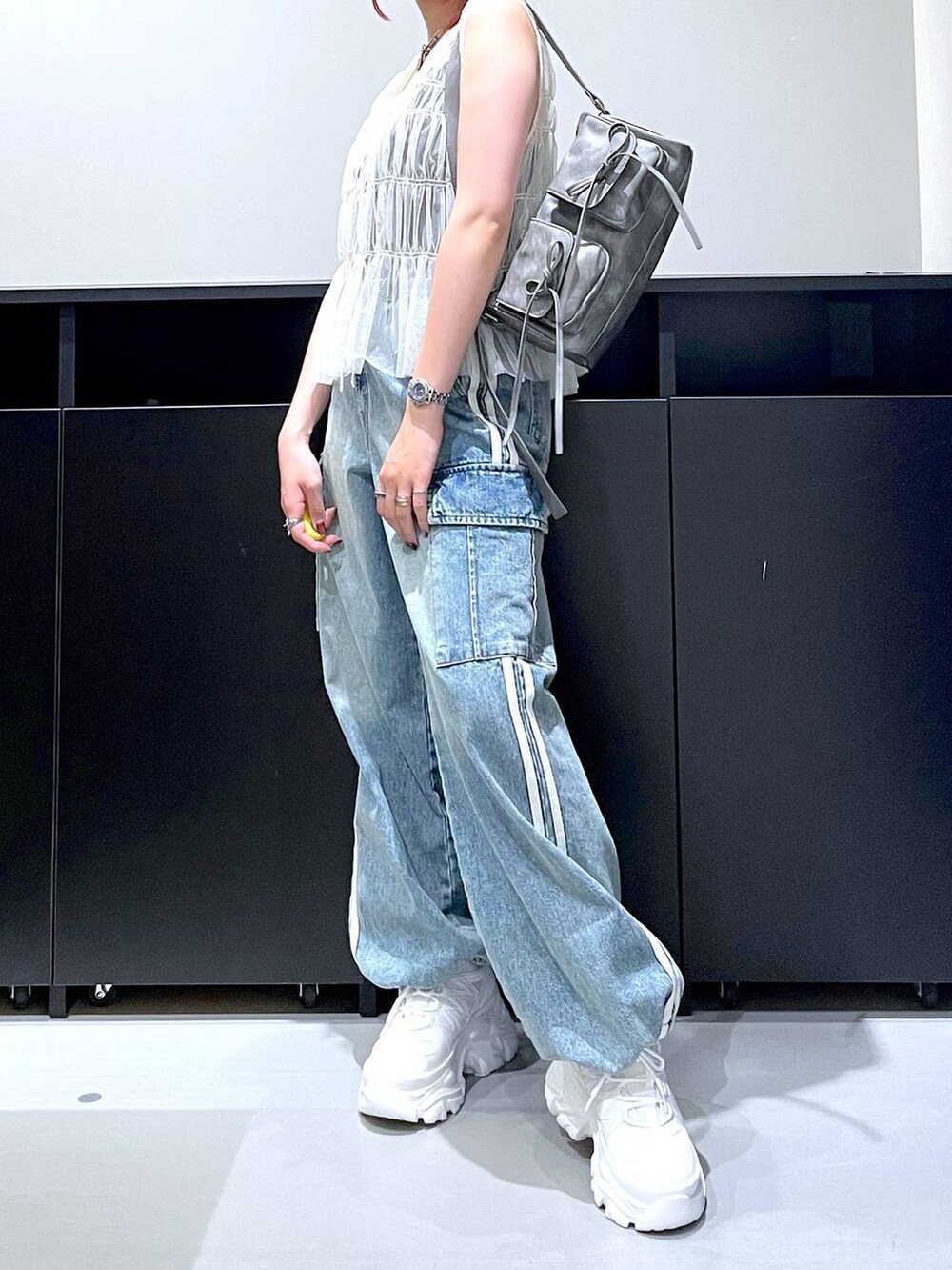 ホワイト系のスニーカー、ブルー系のデニムパンツ、グレー系のショルダーバッグを着用したレディースの夏コーディネートの2枚目の写真