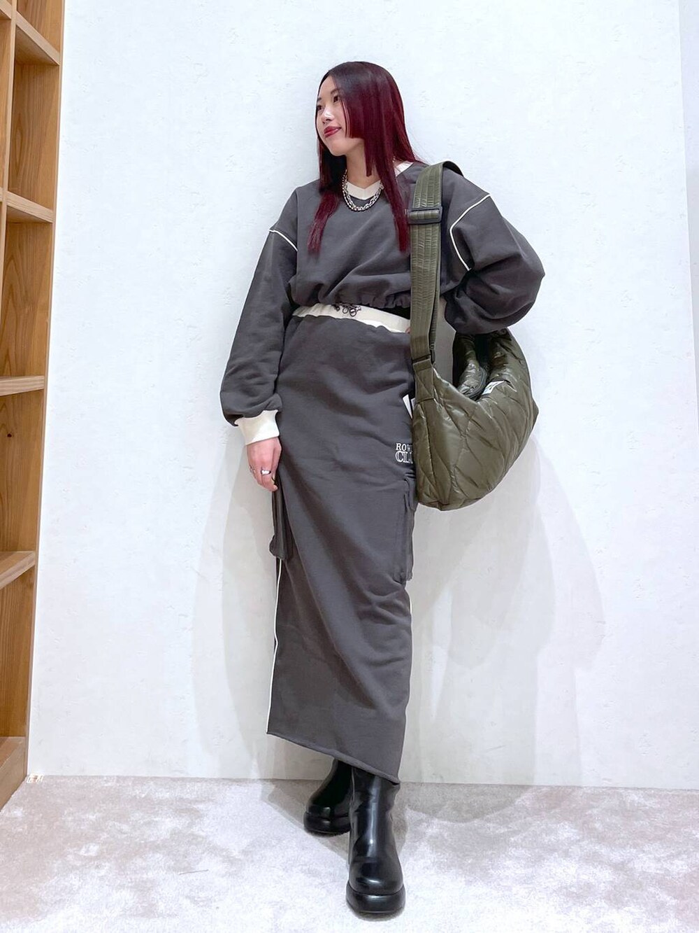 グレー系のスウェット、グレー系のスカート、ブラック系のブーツを着用したレディースの冬コーディネートの2枚目の写真