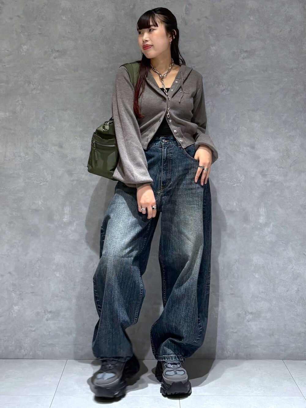 グレー系のスニーカー、グリーン系のボストンバッグ、ブルー系のデニムパンツを着用したレディースの秋コーディネートの9枚目の写真