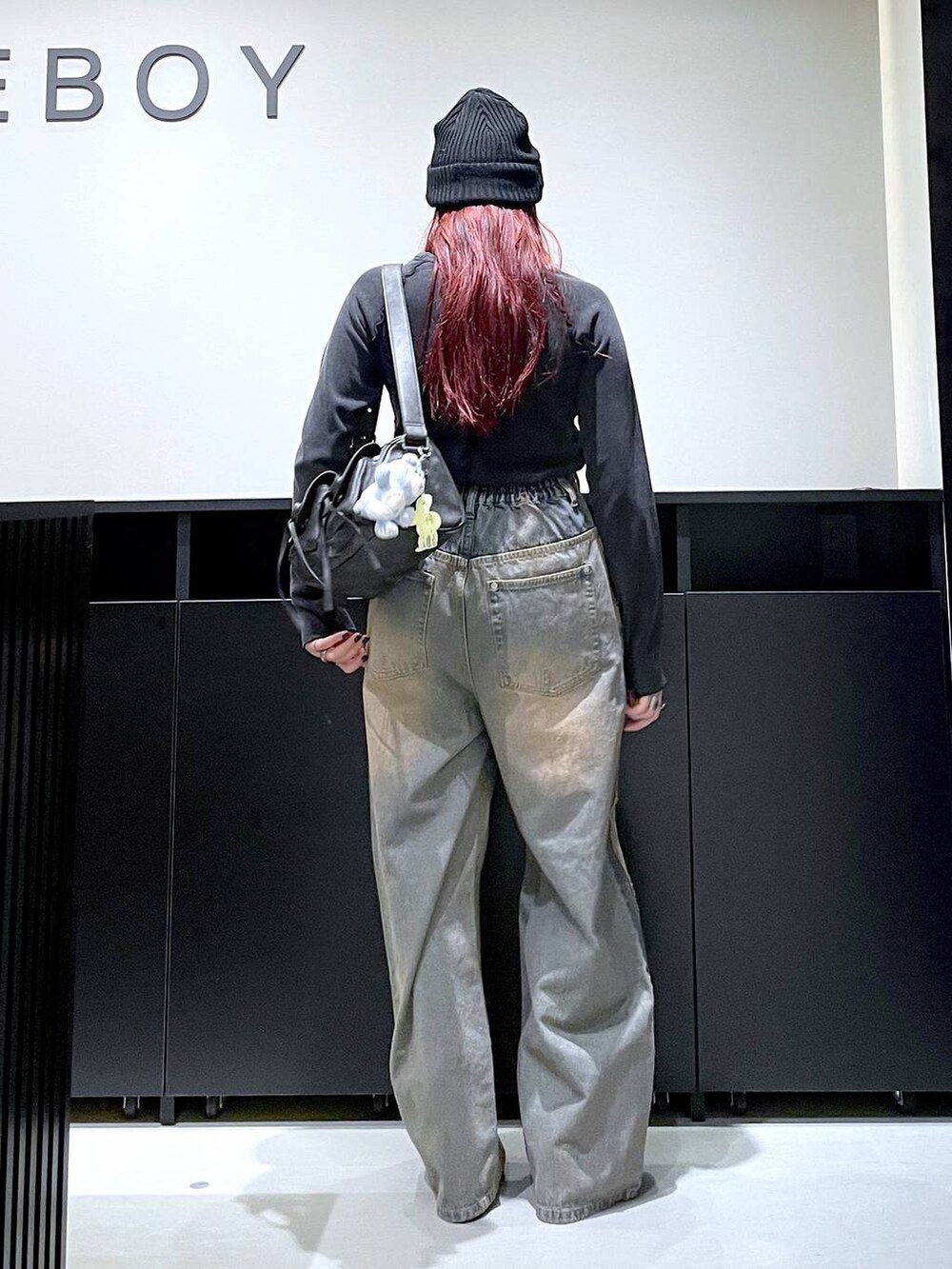 ブラック系のショルダーバッグ、ブルー系のデニムパンツ、ブラック系のブーツを着用したレディースの秋コーディネートの5枚目の写真