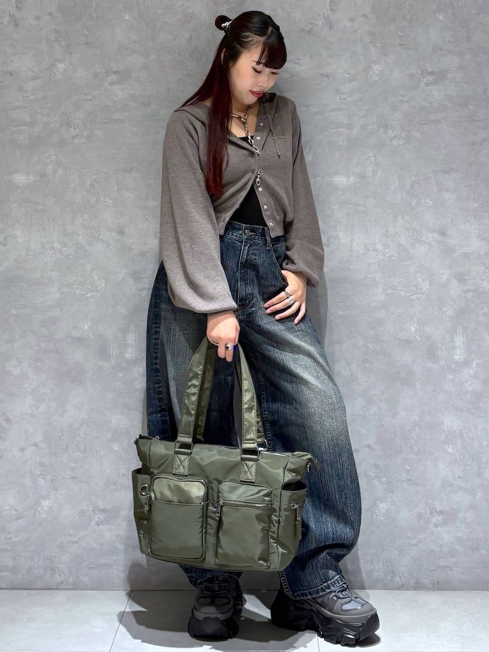 グレー系のスニーカー、グリーン系のボストンバッグ、ブルー系のデニムパンツを着用したレディースの秋コーディネートの7枚目の写真