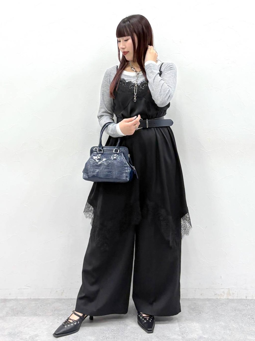 ブルー系のハンドバッグ、ブラック系のスラックス、ブラック系のサンダルを着用したレディースの春コーディネートの2枚目の写真