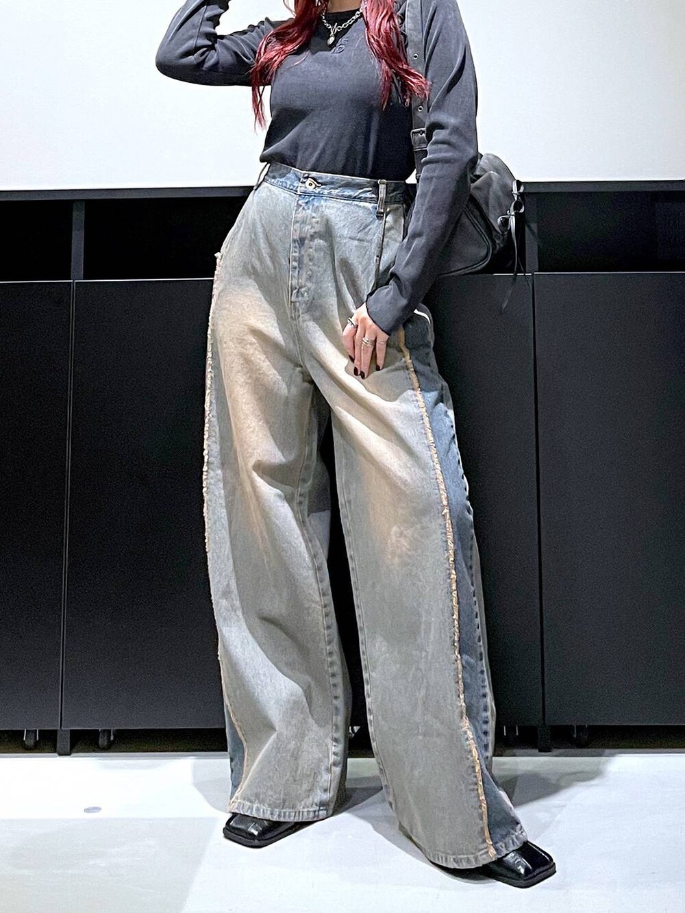 ブラック系のショルダーバッグ、ブルー系のデニムパンツ、ブラック系のブーツを着用したレディースの秋コーディネートの3枚目の写真