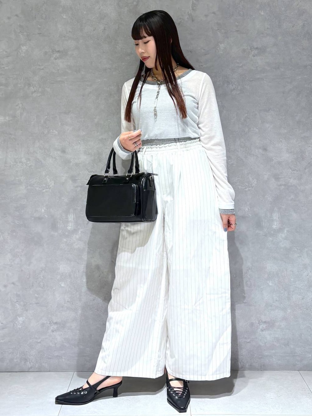 ブラック系のショルダーバッグ、ブラック系のサンダル、ホワイト系のスラックスを着用したレディースの冬コーディネートの6枚目の写真