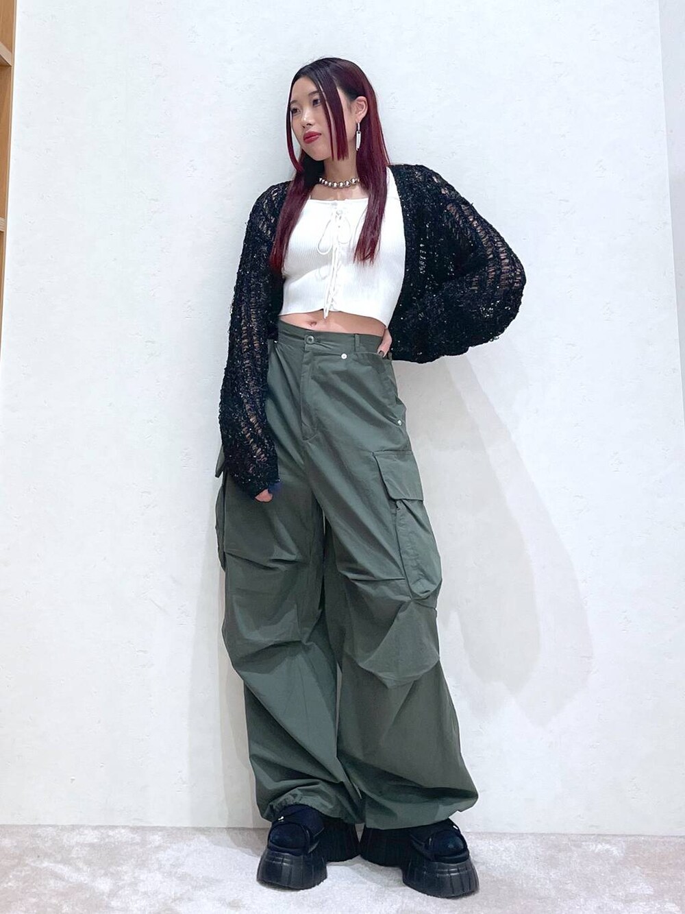 ブラック系のスニーカー、グリーン系のカーゴパンツ、ホワイト系のタンクトップを着用したレディースの春コーディネートの2枚目の写真