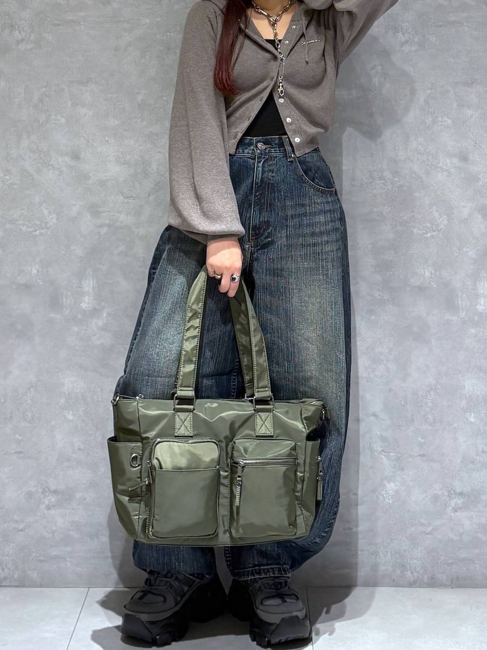 グレー系のスニーカー、グリーン系のボストンバッグ、ブルー系のデニムパンツを着用したレディースの秋コーディネートの3枚目の写真