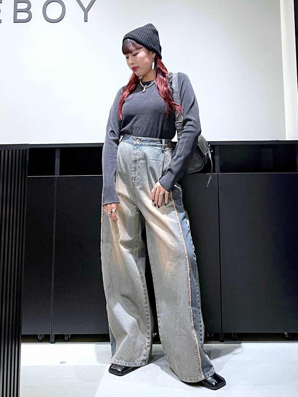 ブラック系のショルダーバッグ、ブルー系のデニムパンツ、ブラック系のブーツを着用したレディースの秋コーディネートの7枚目の写真