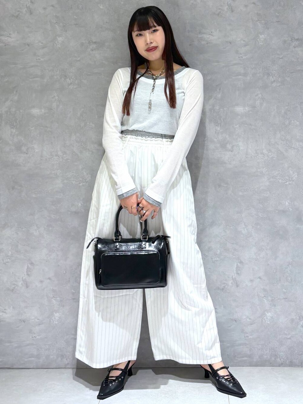 ブラック系のショルダーバッグ、ブラック系のサンダル、ホワイト系のスラックスを着用したレディースの冬コーディネートの8枚目の写真