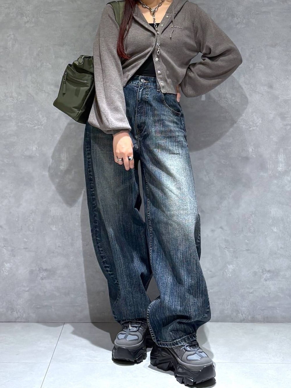 グレー系のスニーカー、グリーン系のボストンバッグ、ブルー系のデニムパンツを着用したレディースの秋コーディネートの8枚目の写真