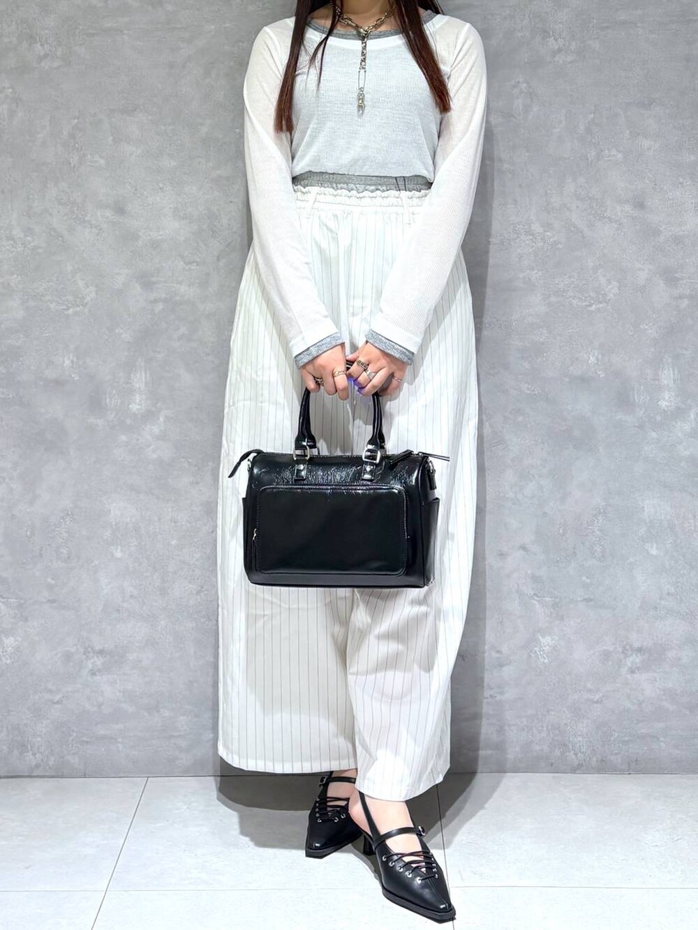ブラック系のショルダーバッグ、ブラック系のサンダル、ホワイト系のスラックスを着用したレディースの冬コーディネートの7枚目の写真
