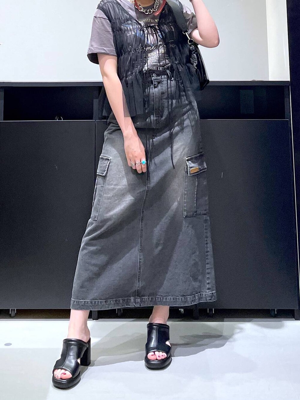 ブラック系のサンダル、ブラック系のデニムスカート、ブラック系のショルダーバッグを着用したレディースの夏コーディネートの2枚目の写真