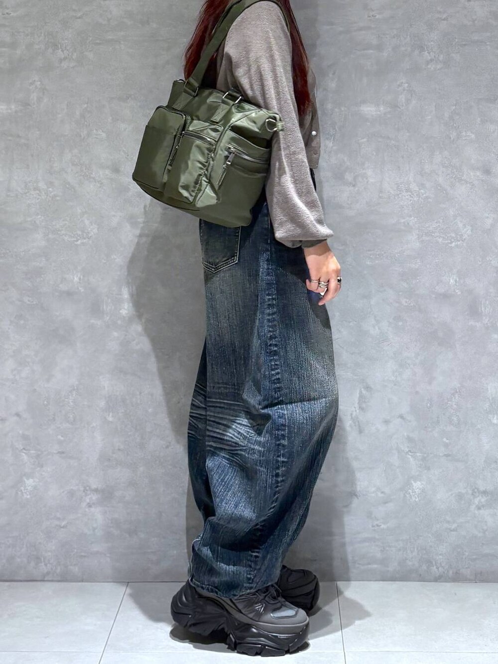 グレー系のスニーカー、グリーン系のボストンバッグ、ブルー系のデニムパンツを着用したレディースの秋コーディネートの6枚目の写真