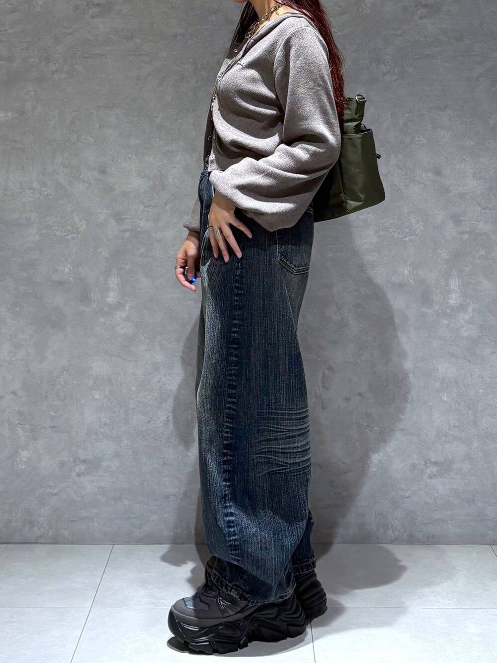 グレー系のスニーカー、グリーン系のボストンバッグ、ブルー系のデニムパンツを着用したレディースの秋コーディネートの4枚目の写真