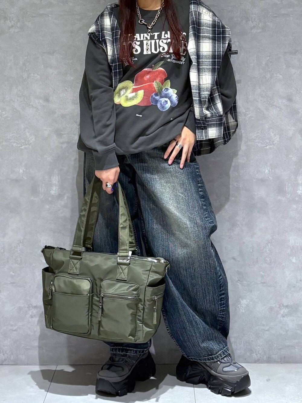 ブラック系のスニーカー、グリーン系のボストンバッグ、ブラック系のスウェットを着用したレディースの秋コーディネートの2枚目の写真