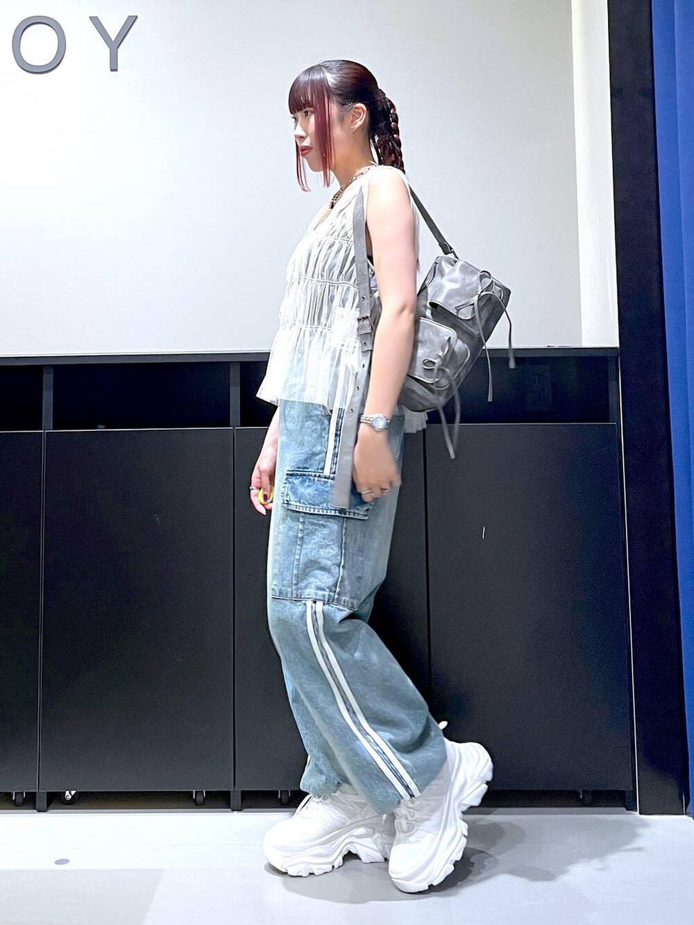 ホワイト系のスニーカー、ブルー系のデニムパンツ、グレー系のショルダーバッグを着用したレディースの夏コーディネートの5枚目の写真