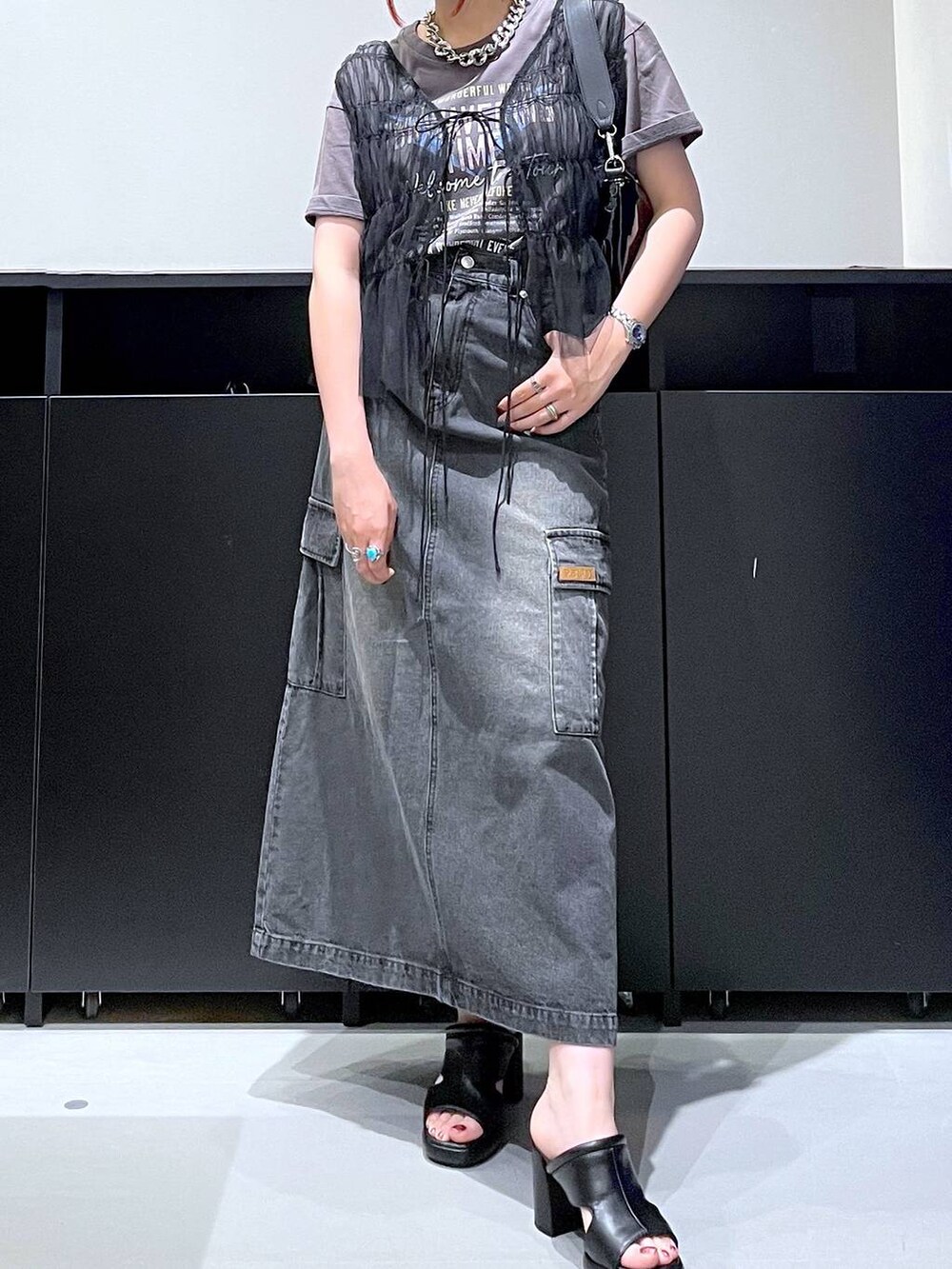 ブラック系のサンダル、ブラック系のデニムスカート、ブラック系のショルダーバッグを着用したレディースの夏コーディネートの4枚目の写真