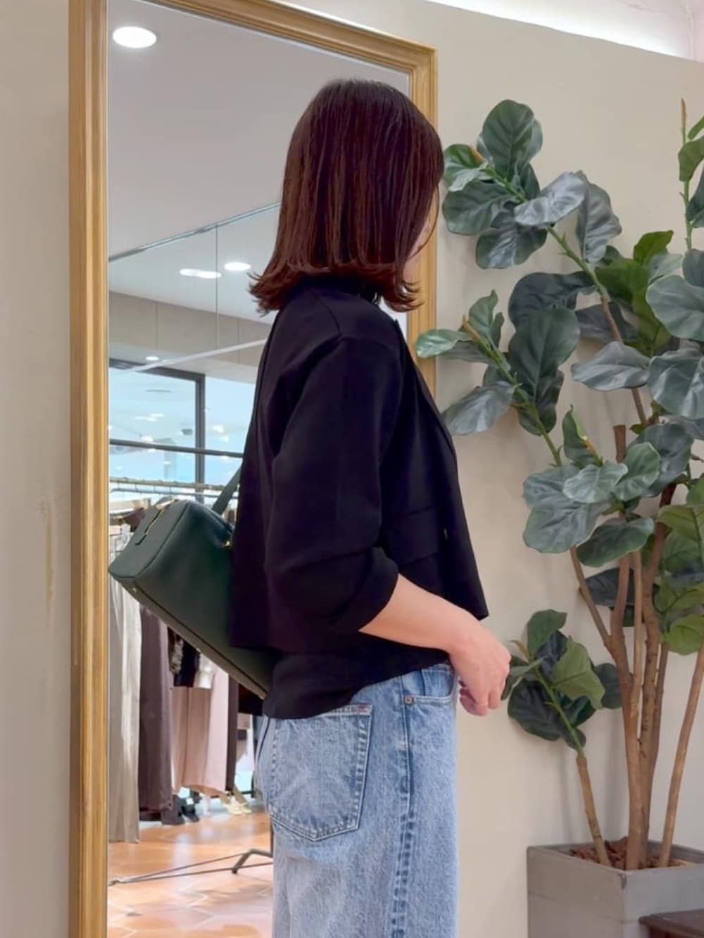 ブラック系のキャミソール、ブラック系のテーラードジャケット、ブルー系のデニムパンツを着用したレディースの夏コーディネートの3枚目の写真