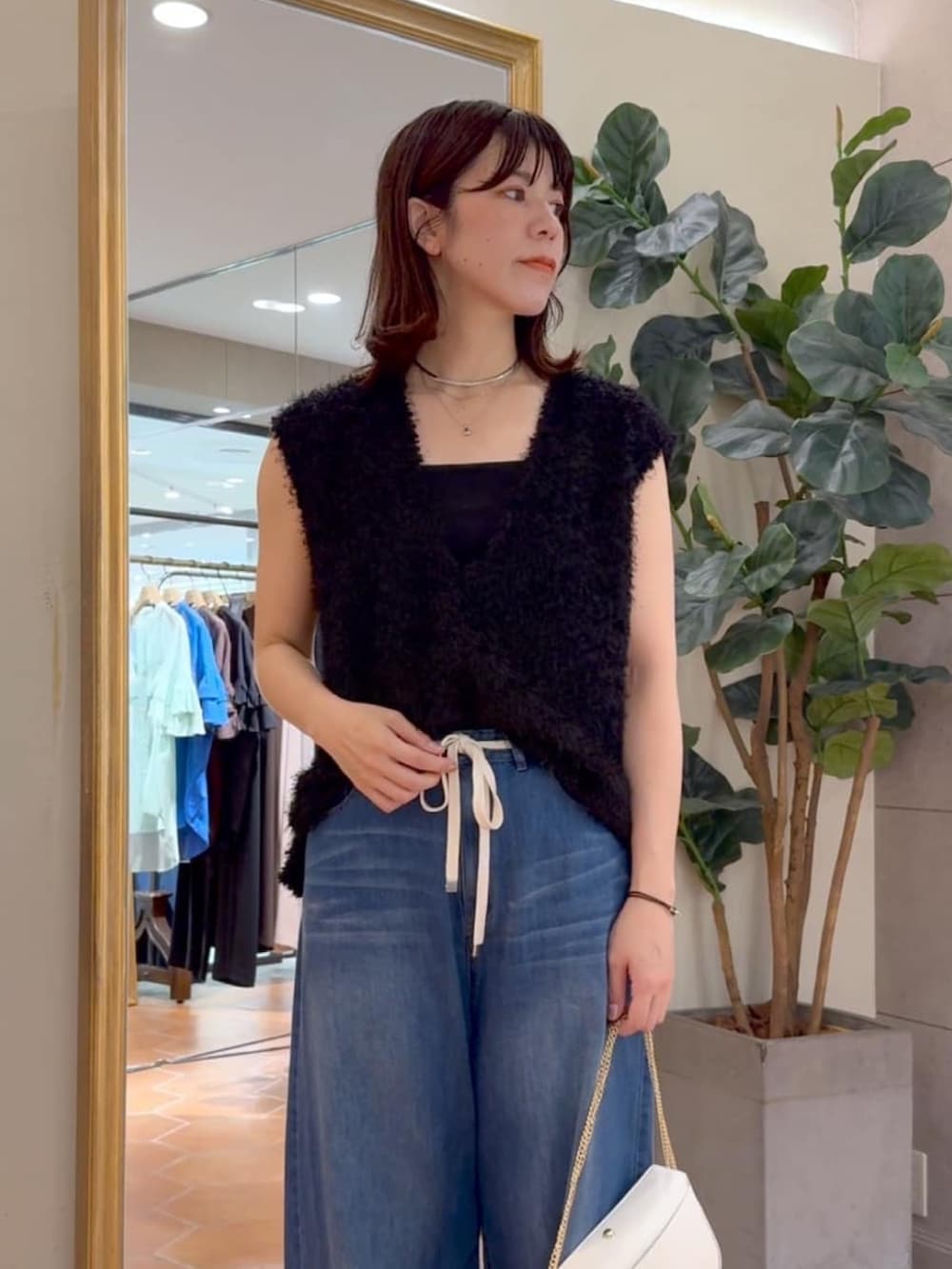 ブラック系のキャミソール、ブラック系のベスト、ブルー系のデニムパンツを着用したレディースの夏コーディネートの2枚目の写真