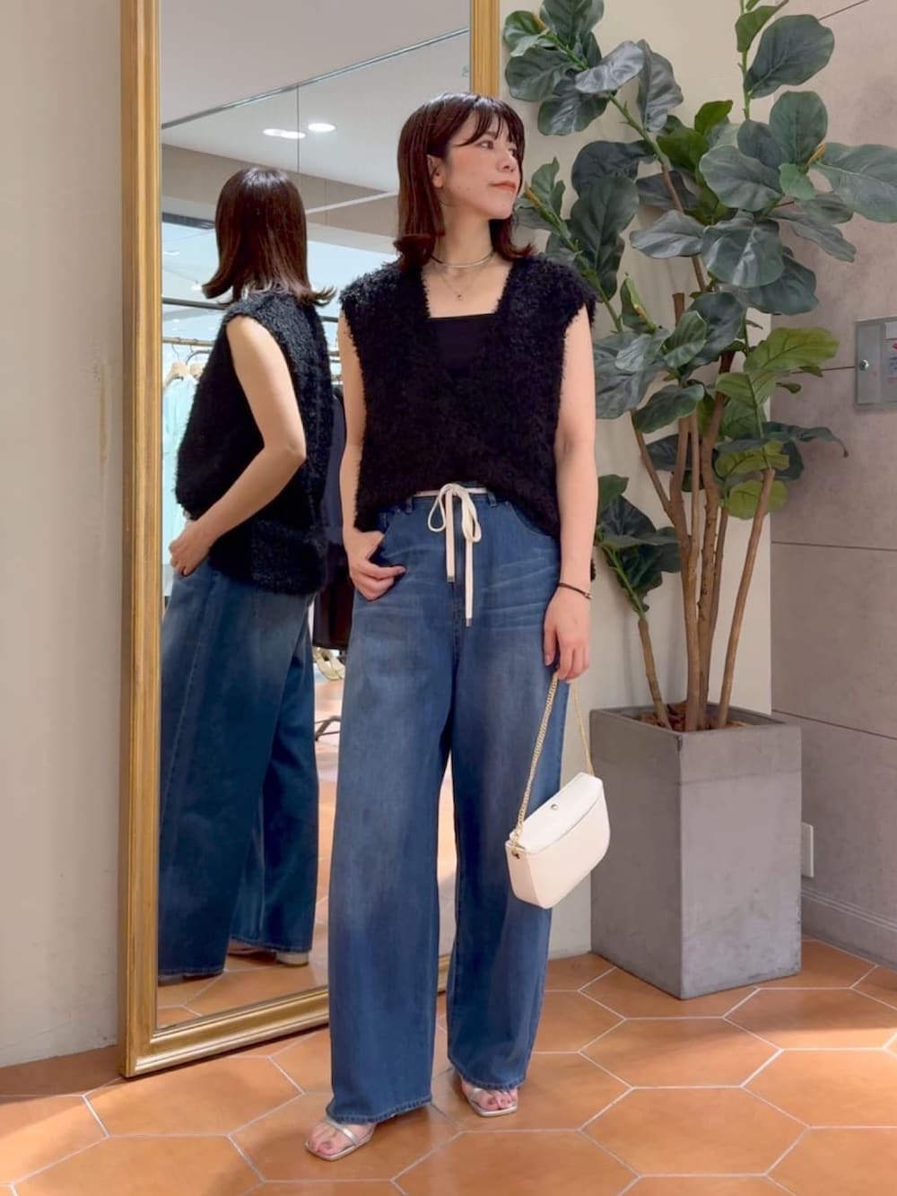 ブラック系のキャミソール、ブラック系のベスト、ブルー系のデニムパンツを着用したレディースの夏コーディネートの5枚目の写真