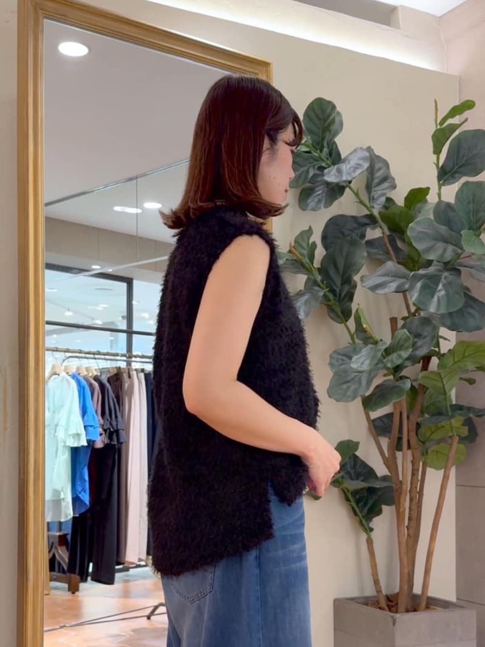 ブラック系のキャミソール、ブラック系のベスト、ブルー系のデニムパンツを着用したレディースの夏コーディネートの3枚目の写真