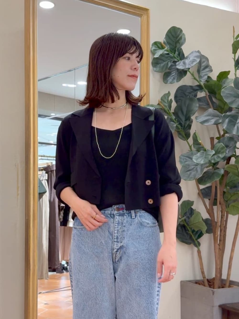 ブラック系のキャミソール、ブラック系のテーラードジャケット、ブルー系のデニムパンツを着用したレディースの夏コーディネートの2枚目の写真