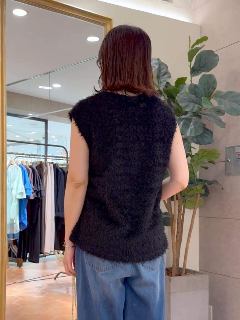 ブラック系のキャミソール、ブラック系のベスト、ブルー系のデニムパンツを着用したレディースの夏コーディネートの4枚目の写真