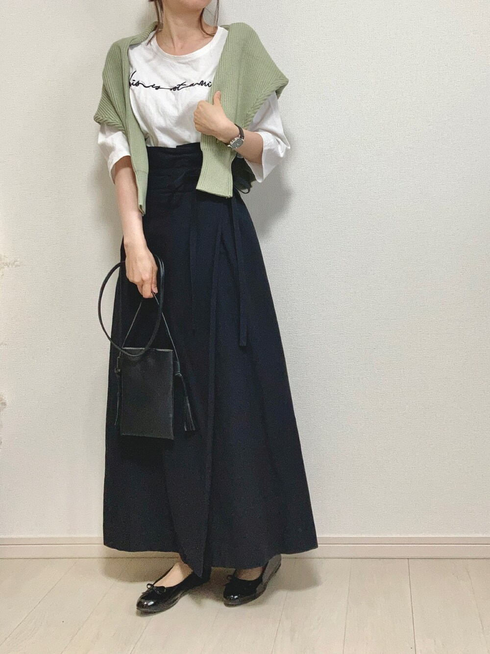 グリーン系のニット/セーター、ホワイト系のTシャツ/カットソー、ブラック系のスカートを着用したレディースの春コーディネートの2枚目の写真