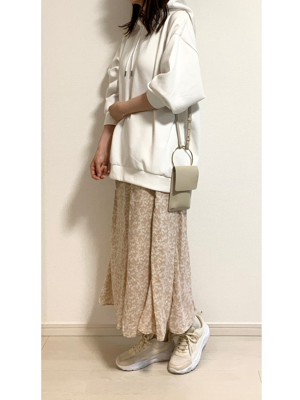 ホワイト系のパーカー、ベージュ系のスカート、ベージュ系のショルダーバッグを着用したレディースの春コーディネートの3枚目の写真