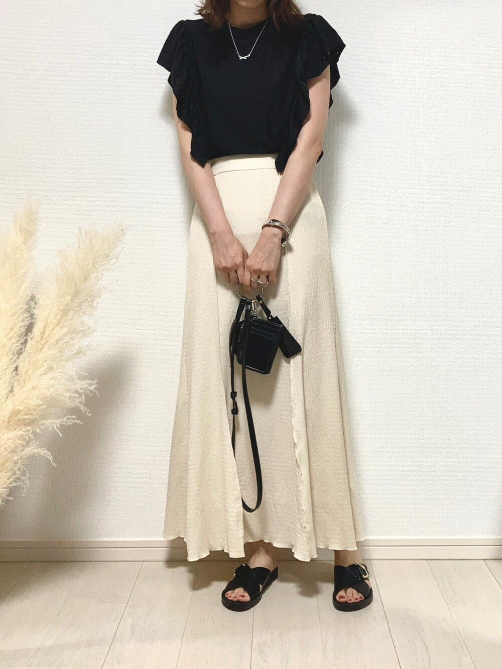 ブラック系のTシャツ/カットソー、ホワイト系のスカート、ブラック系のサンダルを着用したレディースの夏コーディネートの2枚目の写真