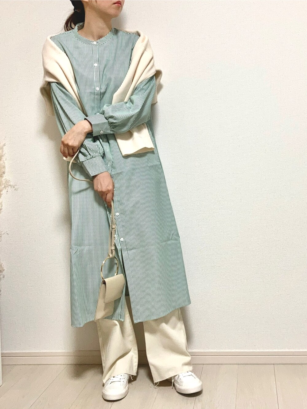 グリーン系のワンピース、ベージュ系のショルダーバッグ、ホワイト系のデニムパンツを着用したレディースの春コーディネートの2枚目の写真