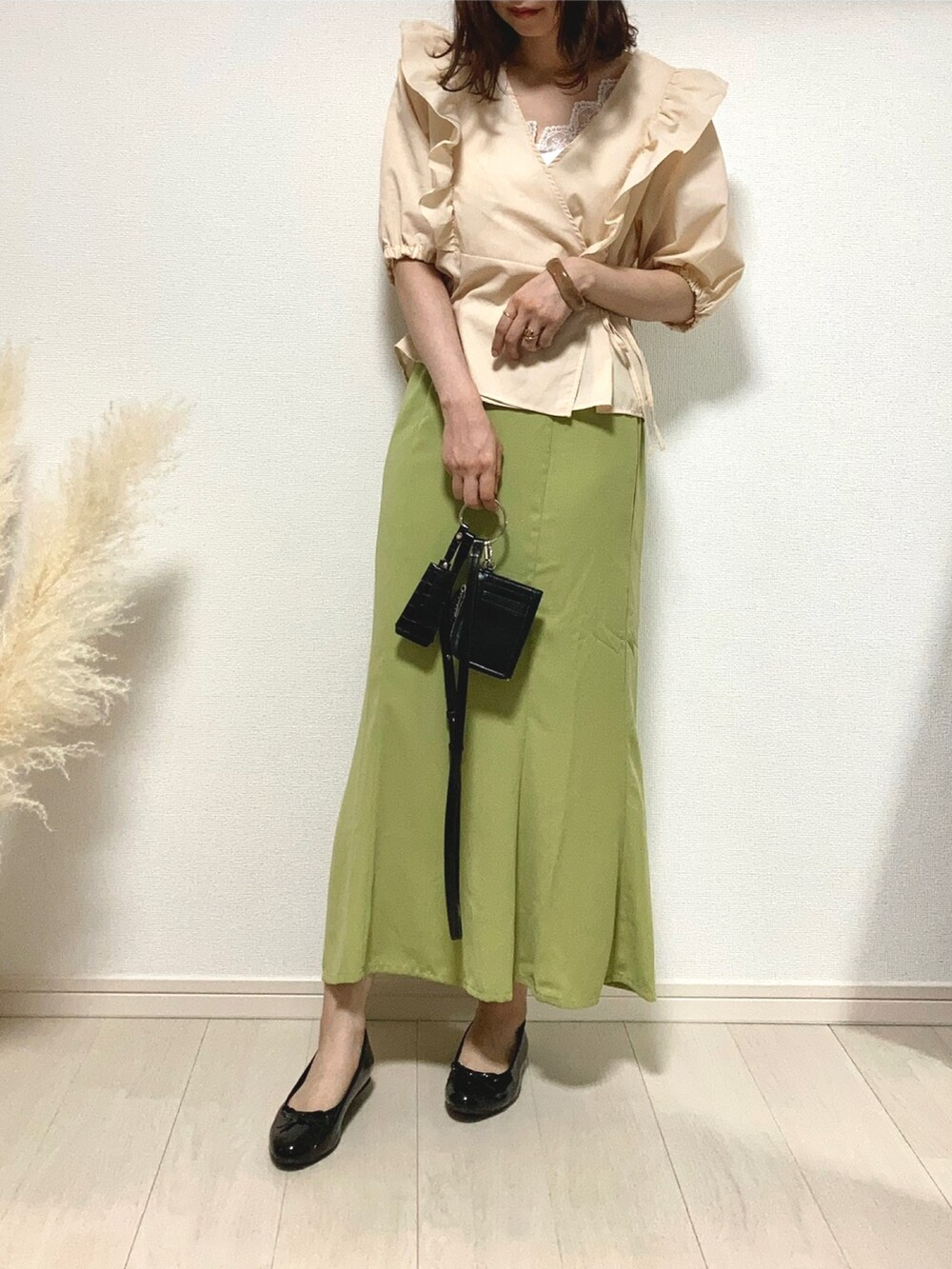 グリーン系のスカート、ブラック系のパンプス、ブラック系のショルダーバッグを着用したレディースの秋コーディネートの2枚目の写真