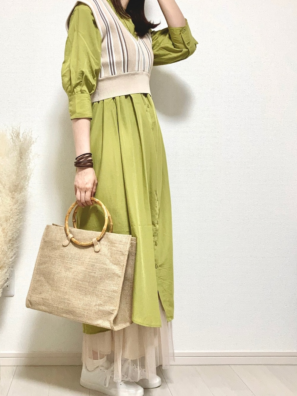 グリーン系のシャツワンピース、ベージュ系のベスト、ベージュ系のハンドバッグを着用したレディースの春コーディネートの2枚目の写真