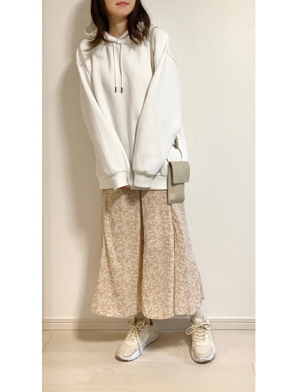 ホワイト系のパーカー、ベージュ系のスカート、ベージュ系のショルダーバッグを着用したレディースの春コーディネートの2枚目の写真