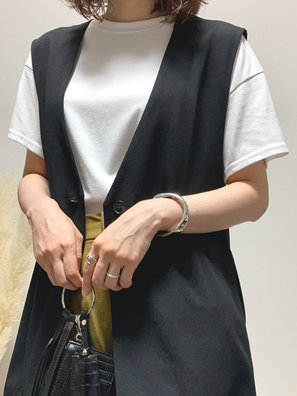 ブラック系のベスト、イエロー系のスラックス、ブラック系のドレスシューズを着用したレディースの夏コーディネートの4枚目の写真