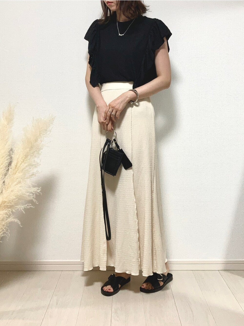 ブラック系のTシャツ/カットソー、ホワイト系のスカート、ブラック系のサンダルを着用したレディースの夏コーディネートの3枚目の写真