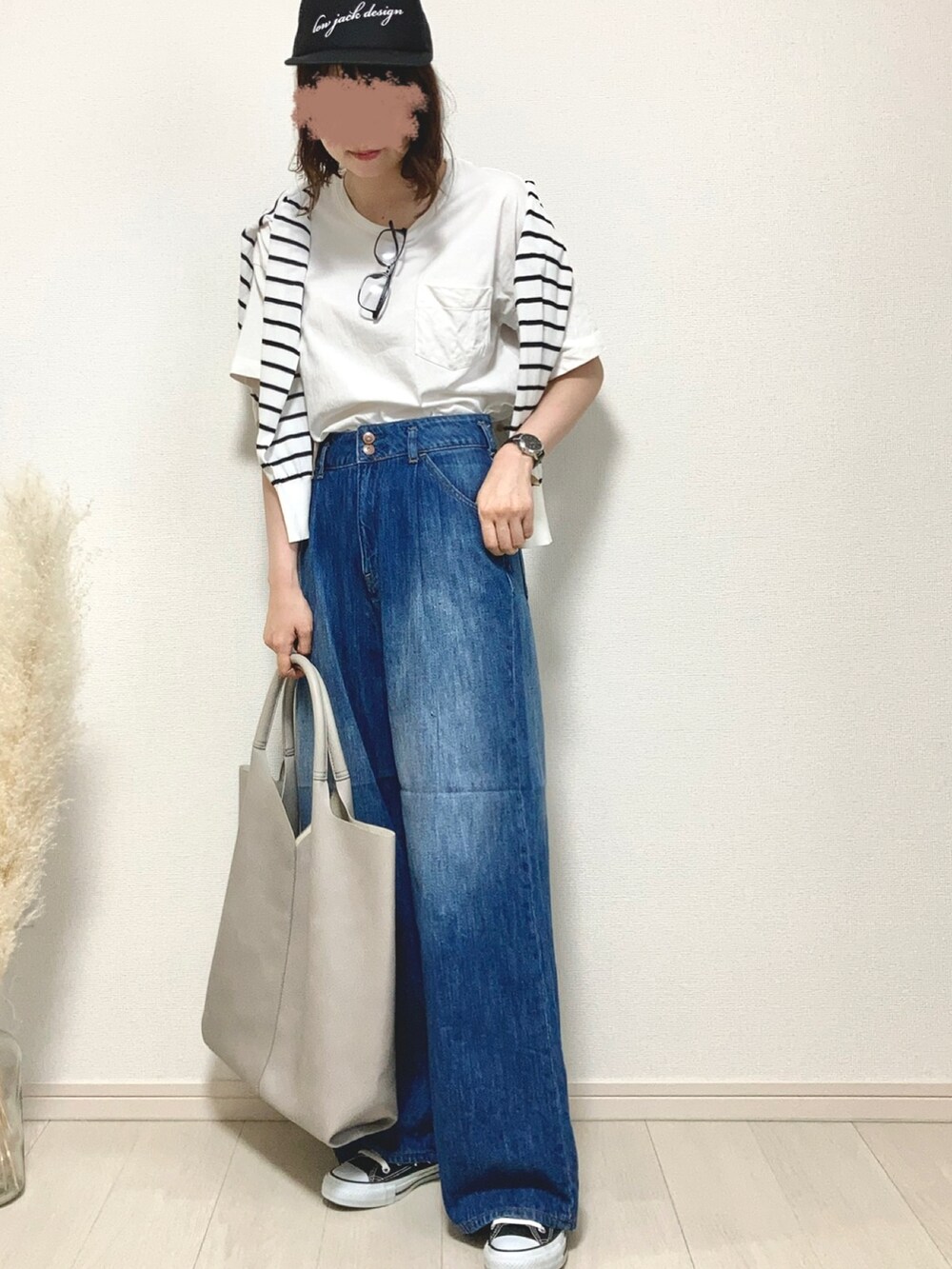 ホワイト系のトートバッグ、ブルー系のデニムパンツ、ブラック系のスニーカーを着用したレディースの夏コーディネートの2枚目の写真