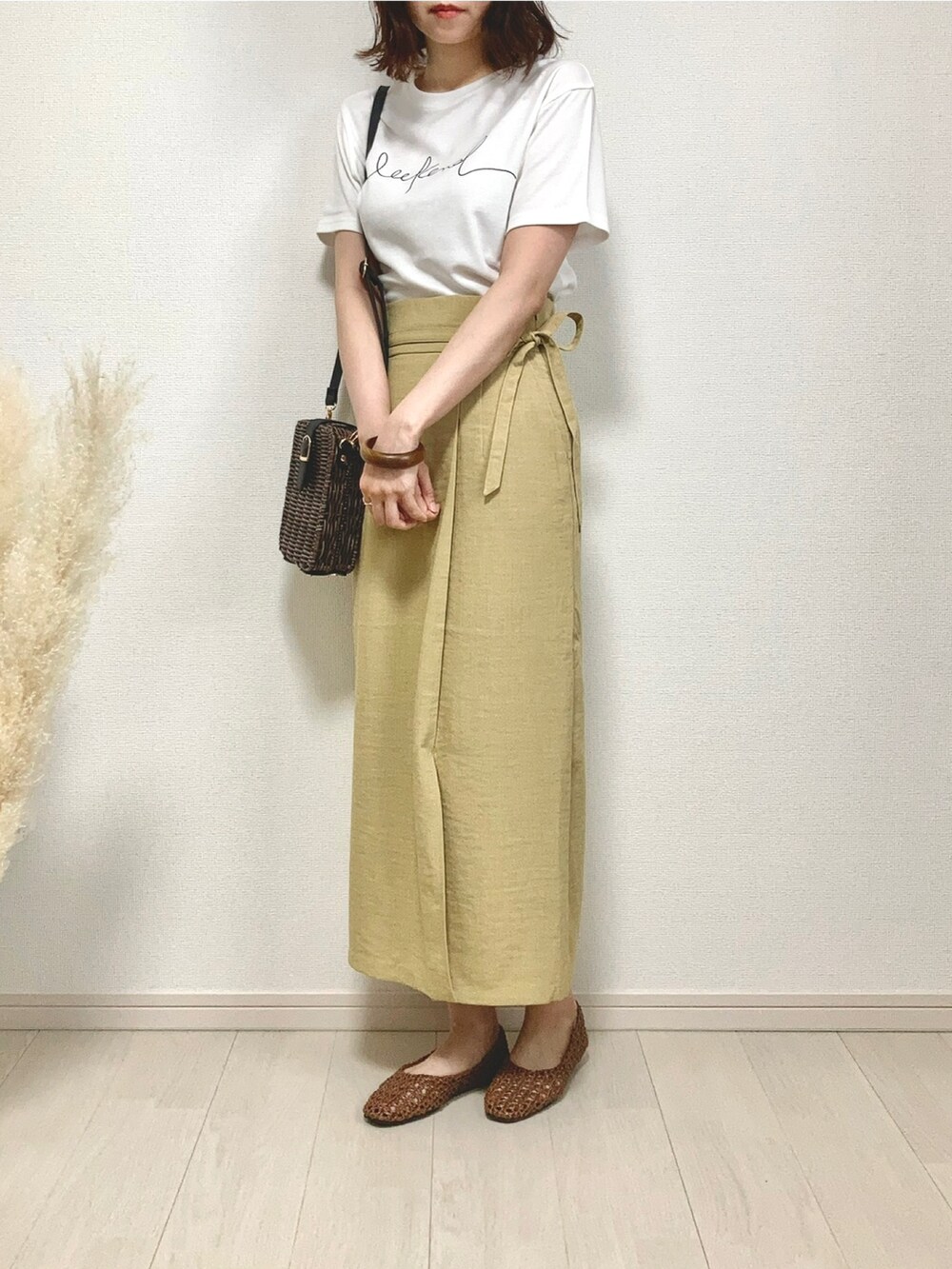 ホワイト系のTシャツ/カットソー、イエロー系のスカート、ブラウン系のかごバッグを着用したレディースの夏コーディネートの3枚目の写真