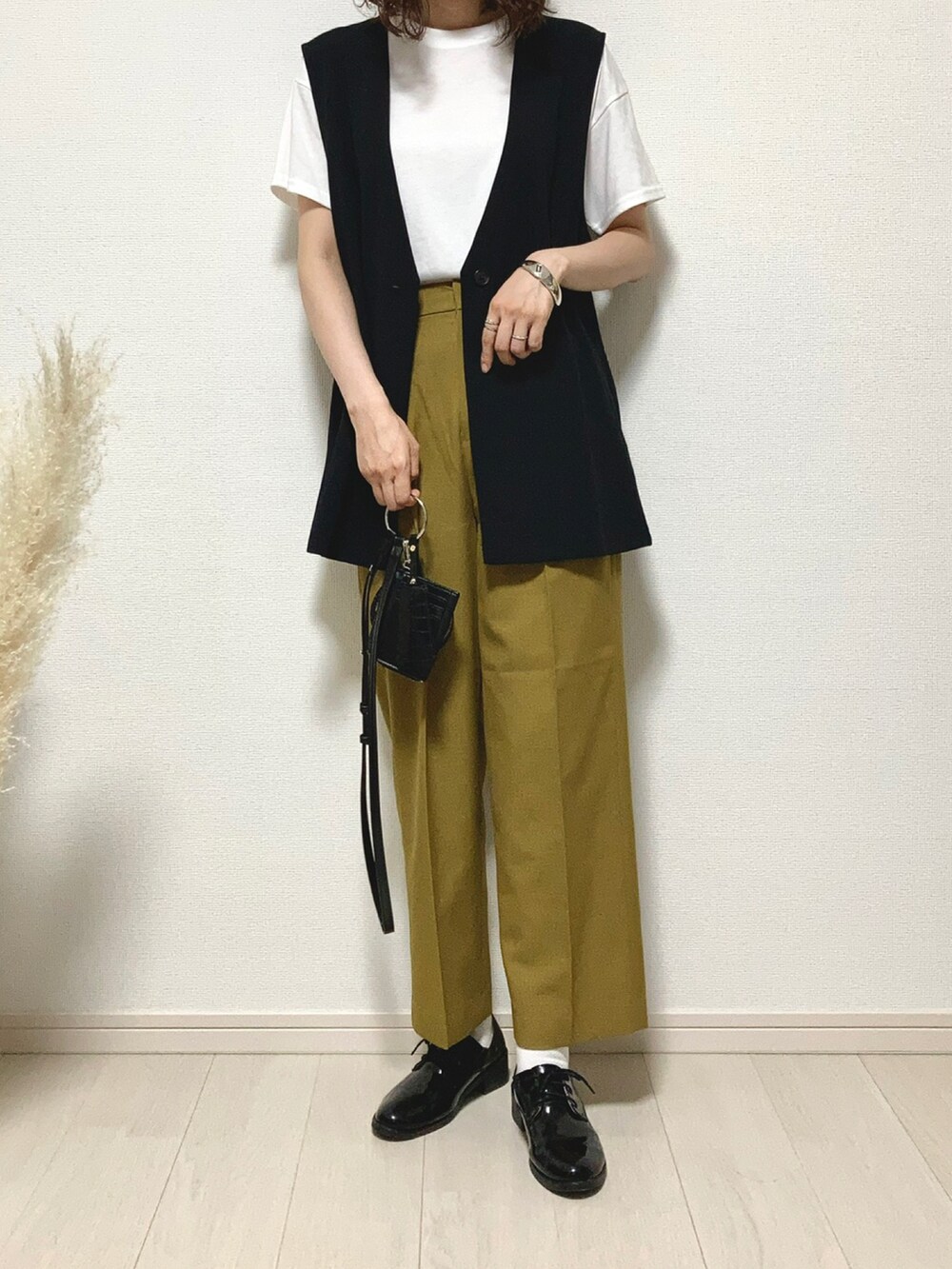 ブラック系のベスト、イエロー系のスラックス、ブラック系のドレスシューズを着用したレディースの夏コーディネートの3枚目の写真