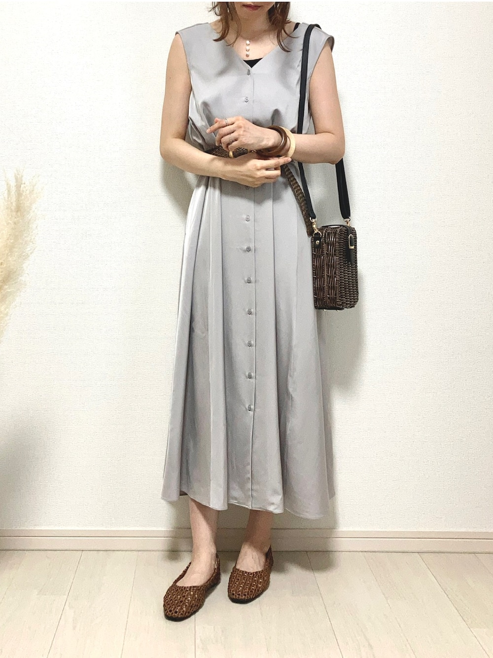 グレー系のワンピース、ブラウン系のパンプス、ブラウン系のかごバッグを着用したレディースの夏コーディネートの2枚目の写真