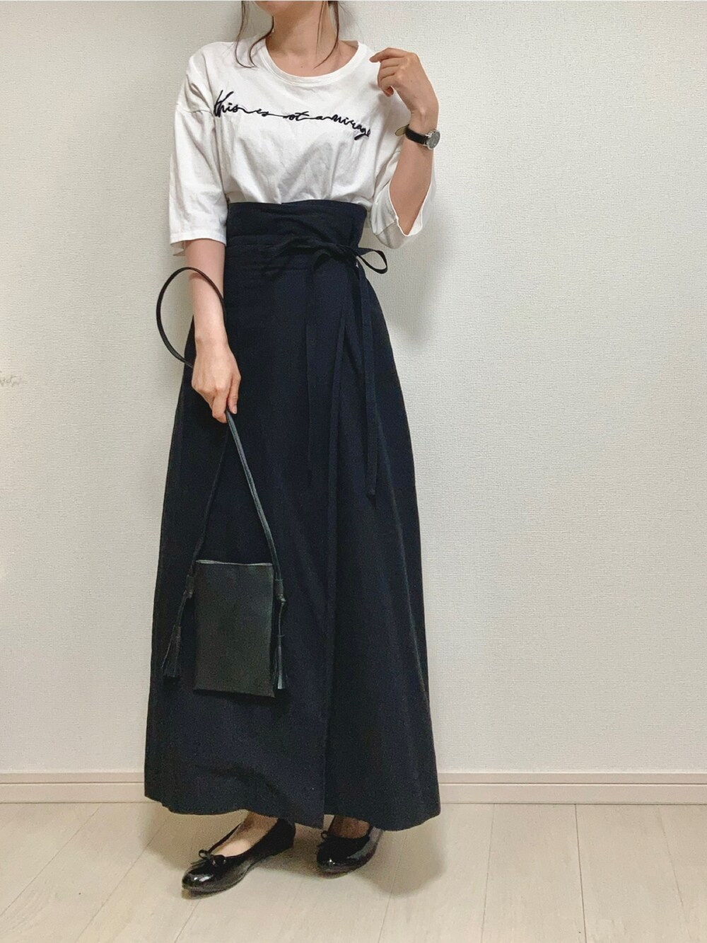 グリーン系のニット/セーター、ホワイト系のTシャツ/カットソー、ブラック系のスカートを着用したレディースの春コーディネートの3枚目の写真