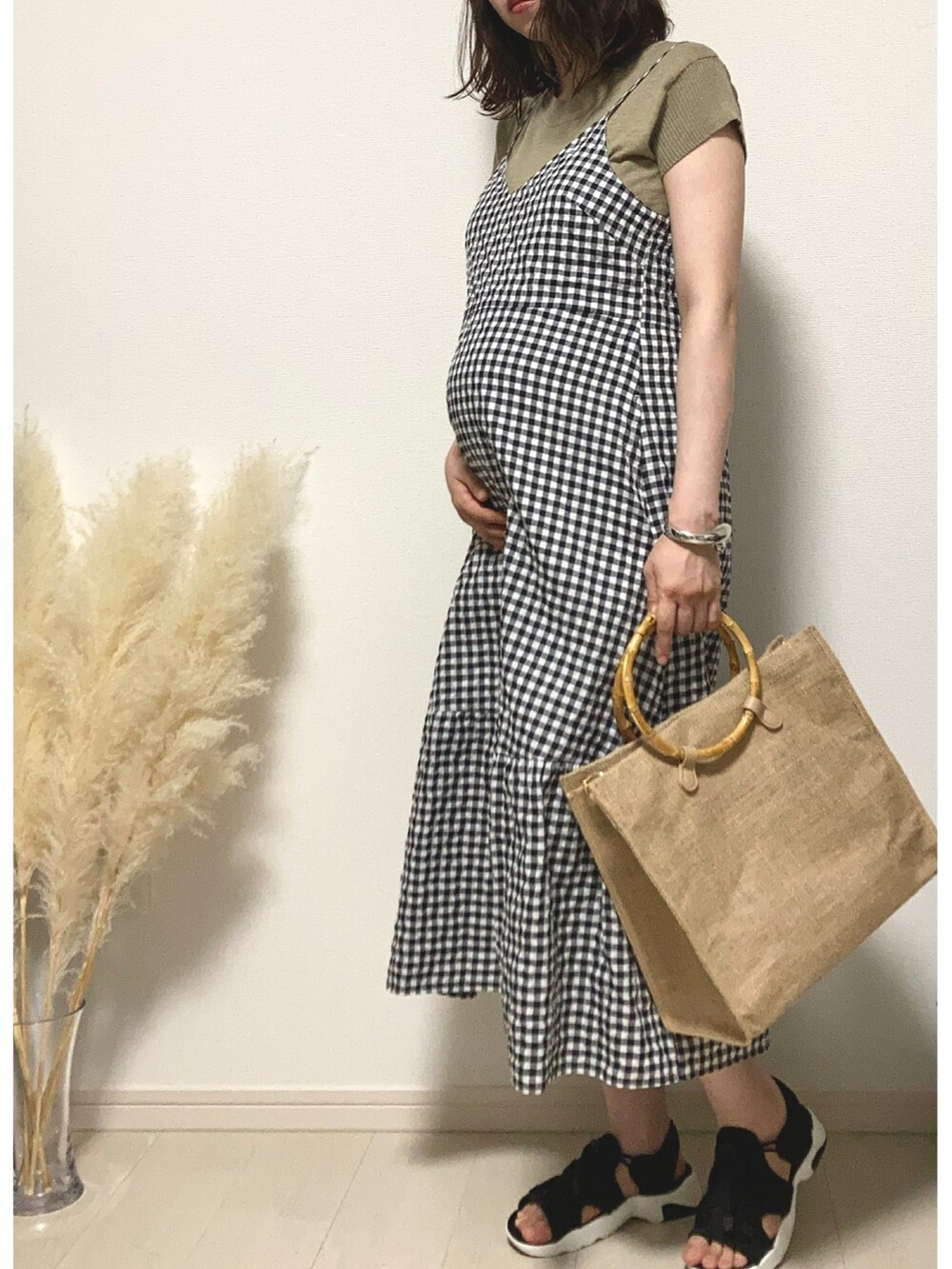 ブラック系のワンピース、ベージュ系のハンドバッグ、ブラック系のサンダルを着用したレディースの夏コーディネートの2枚目の写真